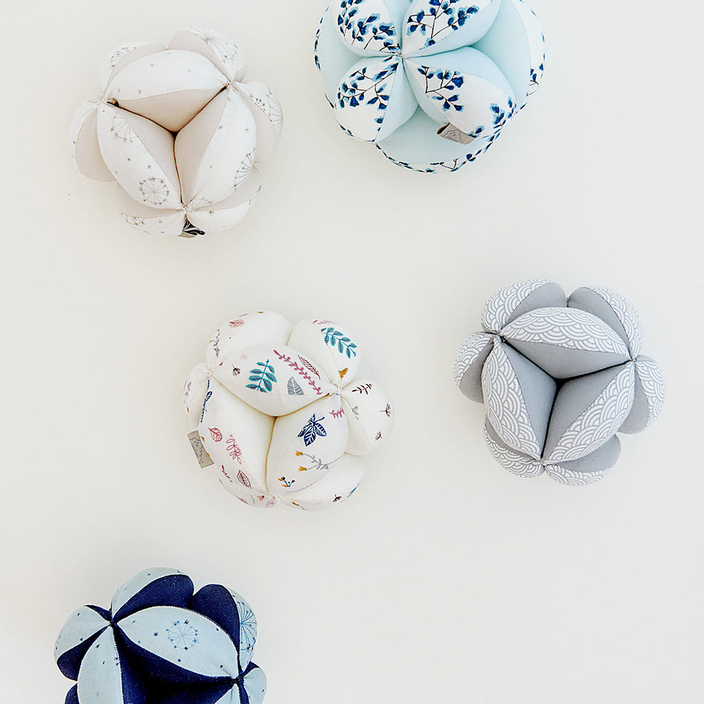 palla montessoriana per neonati in cotone bio stampata con fantasia a fiori insieme ad alltre versioni di colore diverso