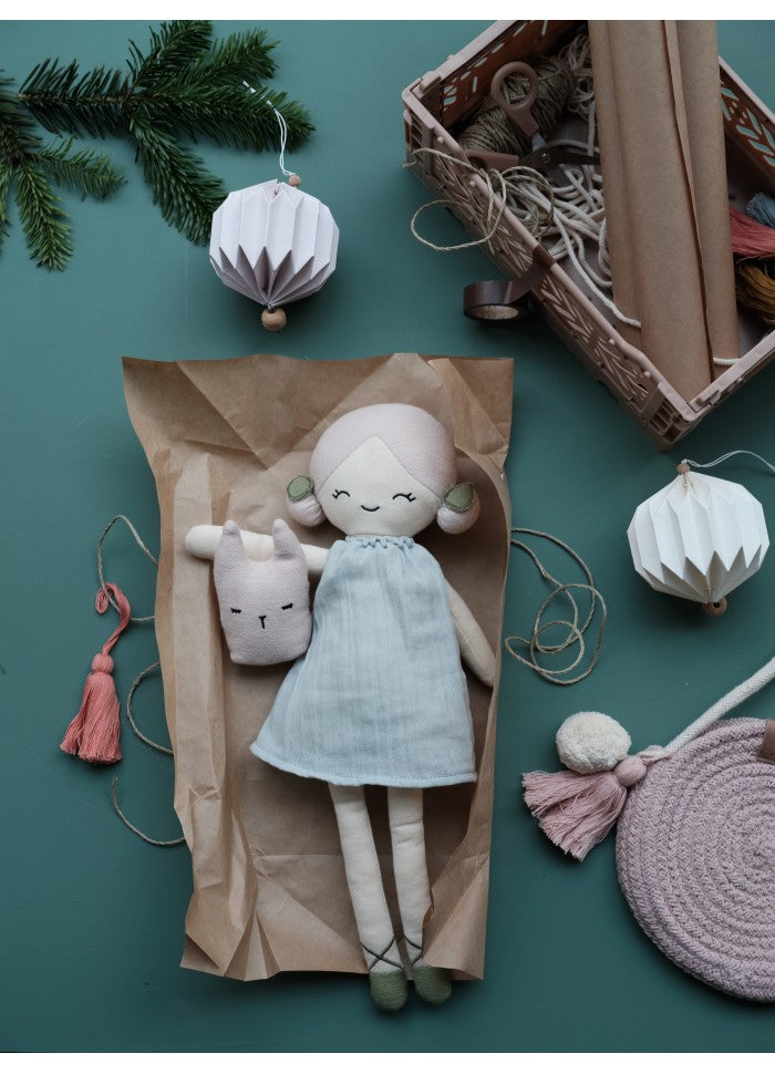 Bambola con eleganti chignon laterali, un abito celeste e scarpette con lacci intrecciati; con altri oggetti