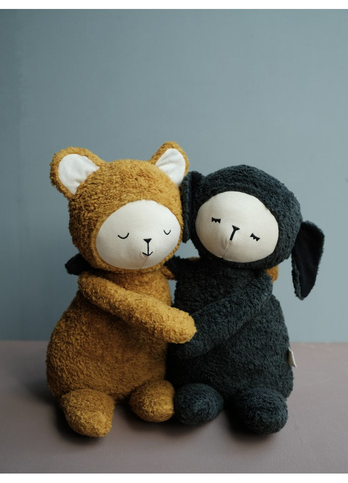 Due peluche (orso ocra e pecora nera) abbracciati