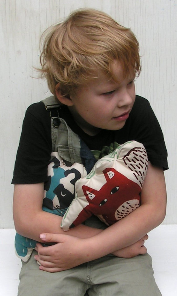 Bambino con in braccio bambola di stoffa a forma di procione con sguardo immalinconito