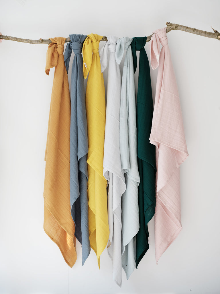 Copertine/swaddle in cotone di vari colori appese ad un filo