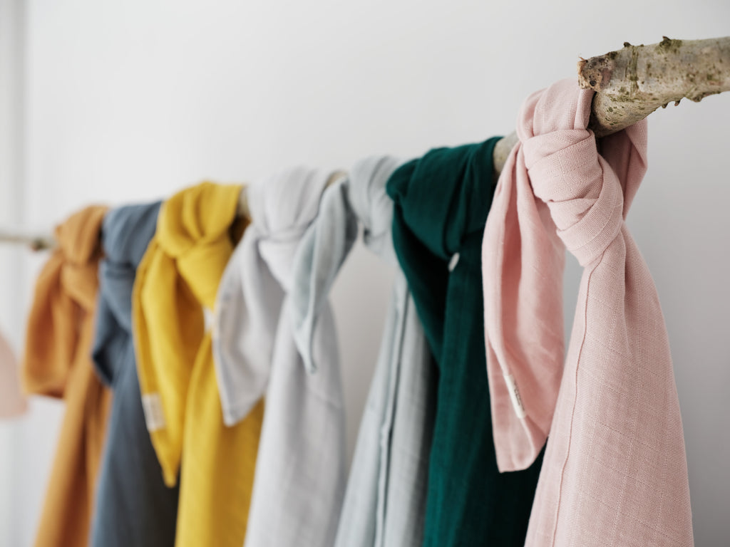 Copertine/swaddle in cotone di vari colori appese ad un filo