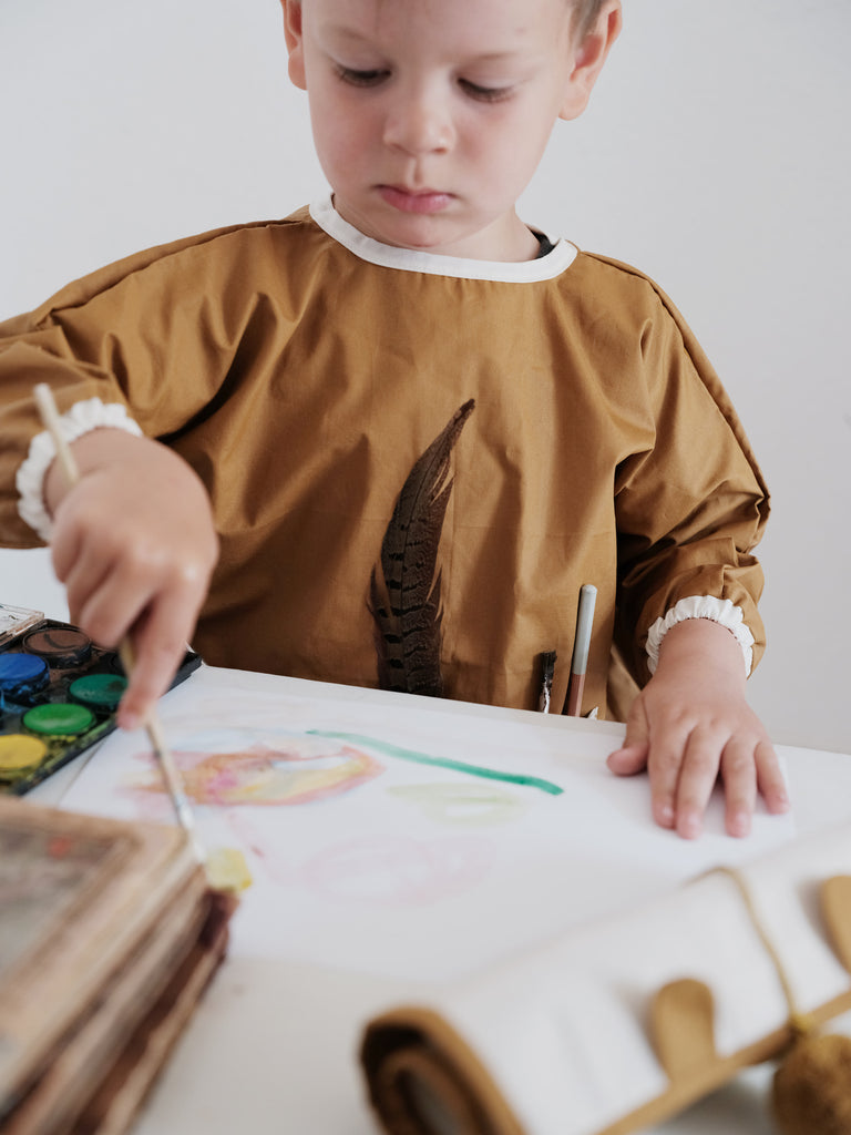 Bambino con indosso grembiulino da pittura color ocra