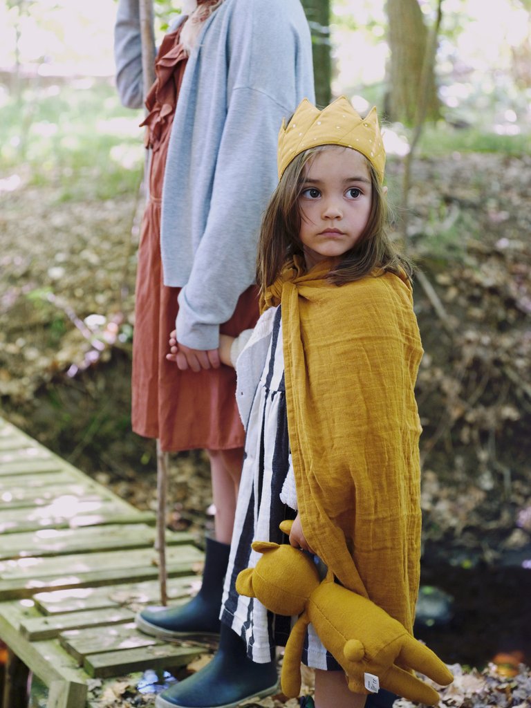 Bambina con la corona di stoffa e mantello
