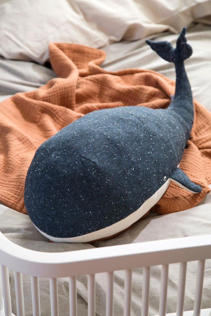 Morbido peluche a forma di balena di un colore blu intenso sopra una copertina in un lettino