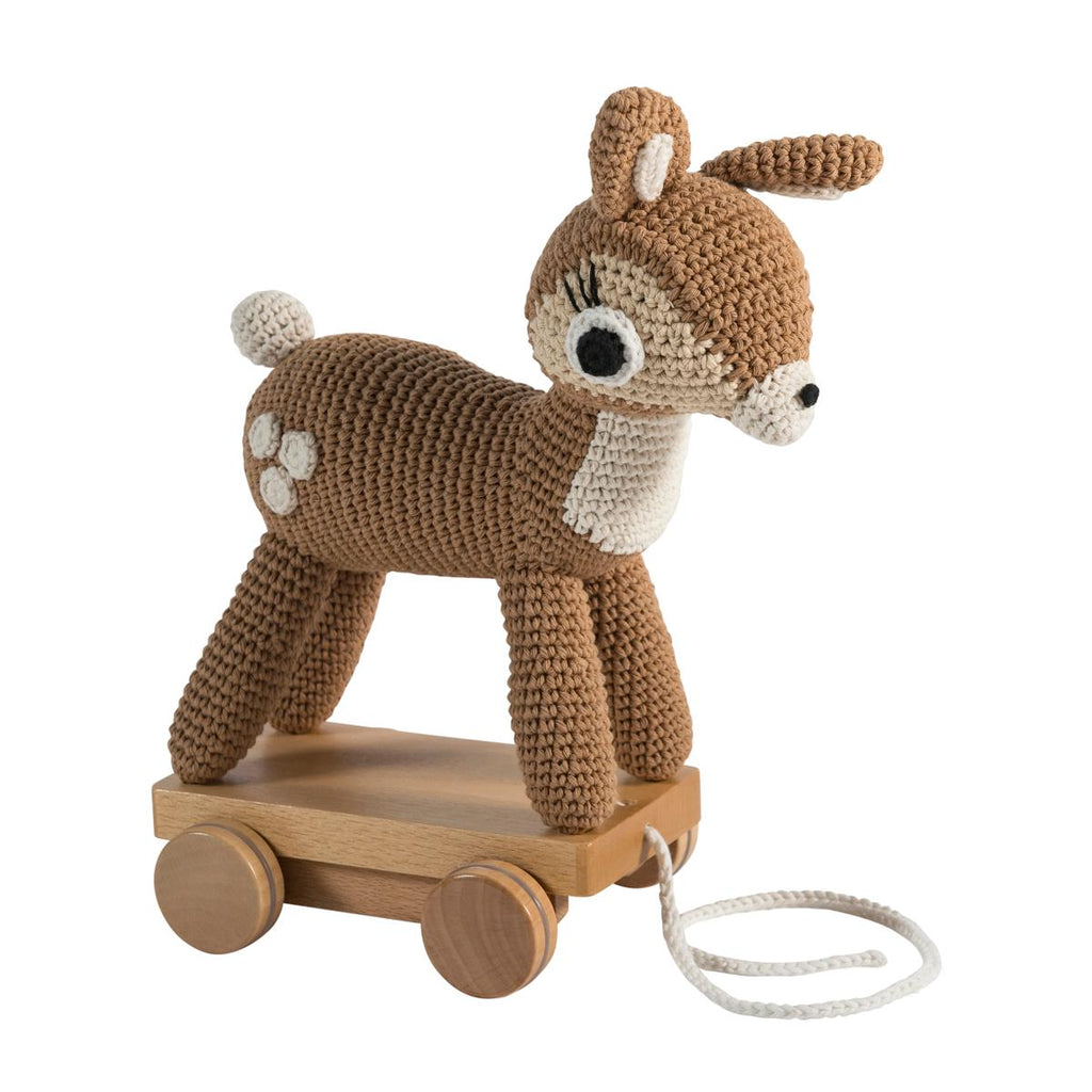 Bambi all'uncinetto in piedi su tavola di legno con ruote, marrone chiaro con macchie bianche