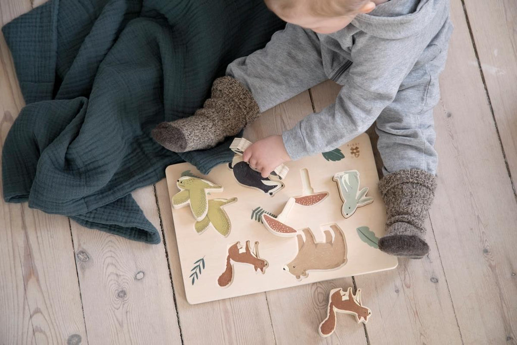 Bambino che gioca con il puzzle in legno ad incastro con tessere animali del bosco