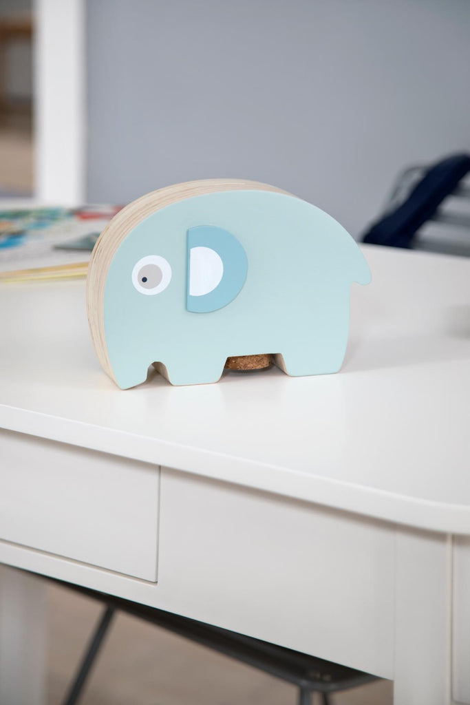Salvadanaio in legno di colore azzurro a forma di elefantino su una scrivania