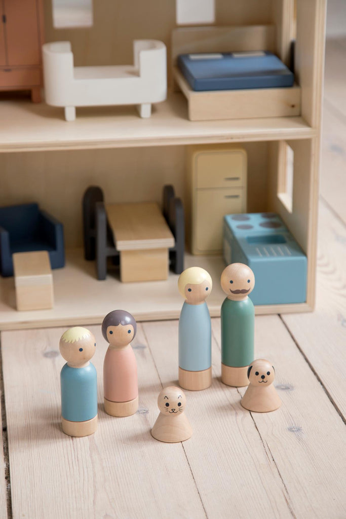 Famiglia di bamboline in legno davanti alla casa delle bambole