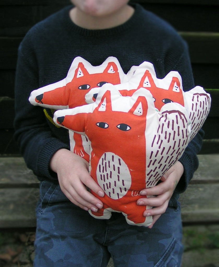 Tre bambole di stoffa a forma di volpe rossa serigrafata a mano in braccio ad un bambino