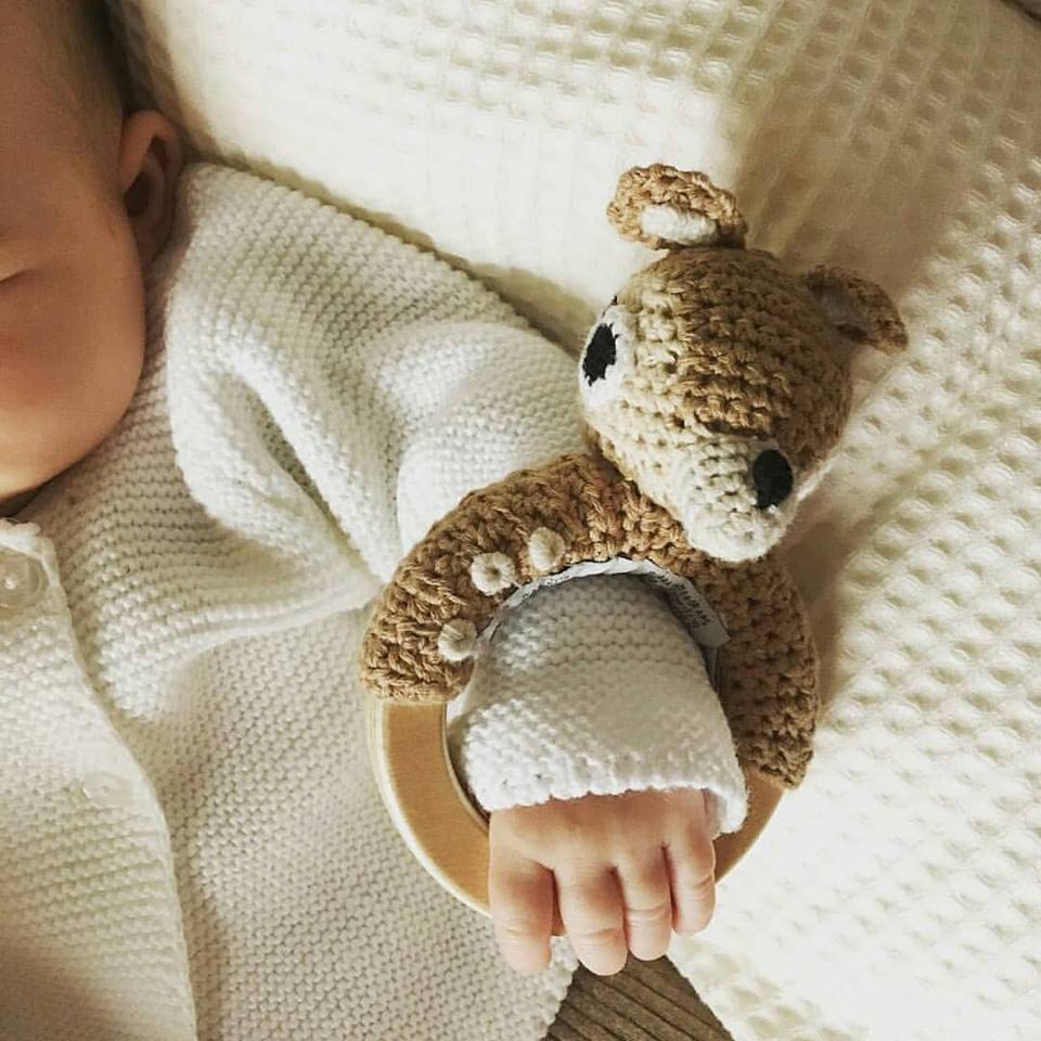 Bambi sonaglio a uncinetto con anello in legno in mano ad un neonato
