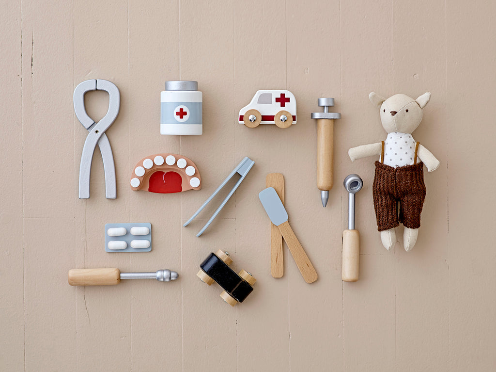 Set di strumenti del dentista in legno: una pinza, una siringa e anche una dentiera, un blister di pastiglie e un tubetto di medicine. Insieme ad un pupazzo e una automobilina ambulanza