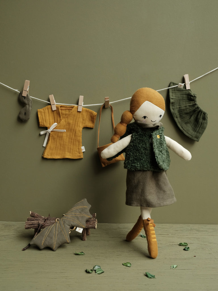 Bambola Ghianda in cotone davanti a vestiti da bambola appesi ad un filo ad asciugare