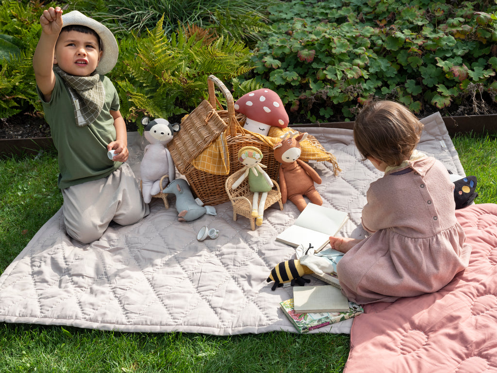 Bambola fatina in cotone biologico insieme ad altri peluche accanto a due bambini che giocano