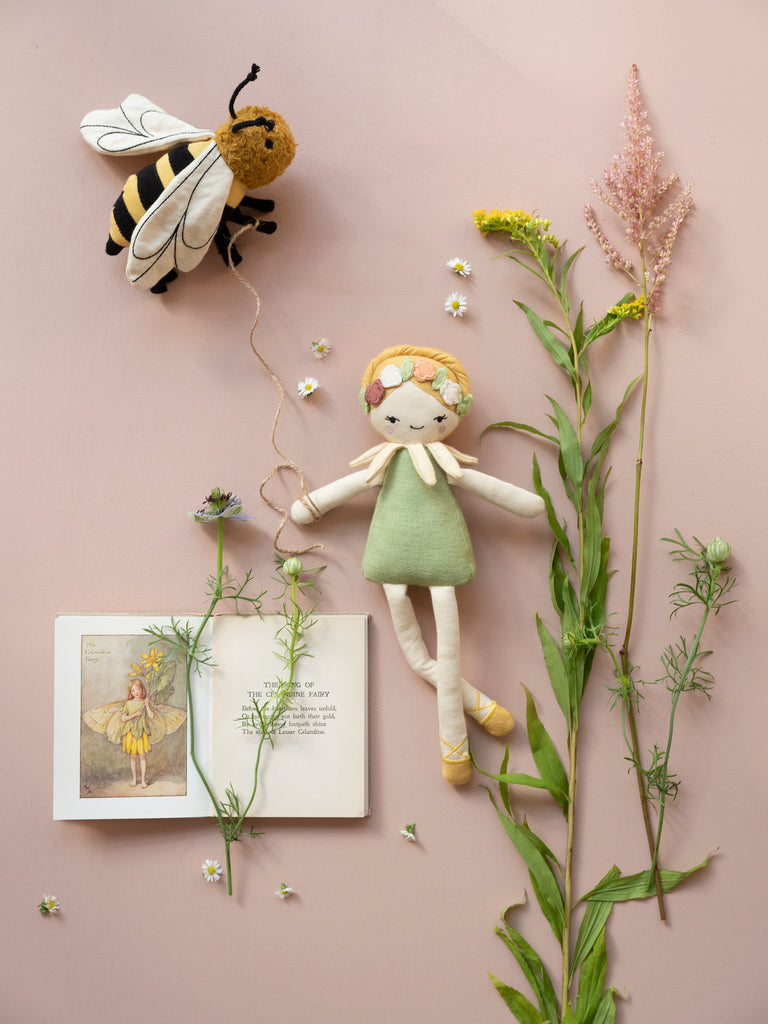 Bambola fatina in cotone biologico appesa ad una parete con altri oggetti