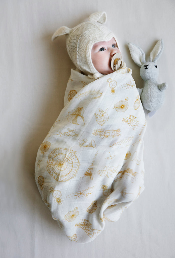 Sonaglio in stoffa a forma di leprotto accanto ad un neonato con cuffia  avvolto in una copertina