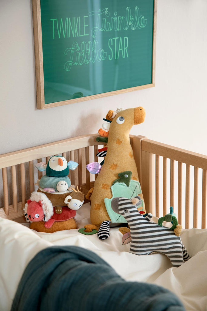 Gioco sensoriale a forma di giraffa in un lettino con altri giocattoli