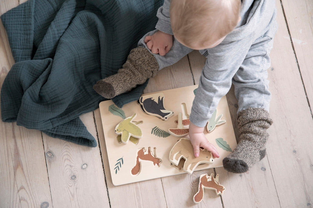 Bambino che gioca con il puzzle in legno ad incastro con tessere animali del bosco