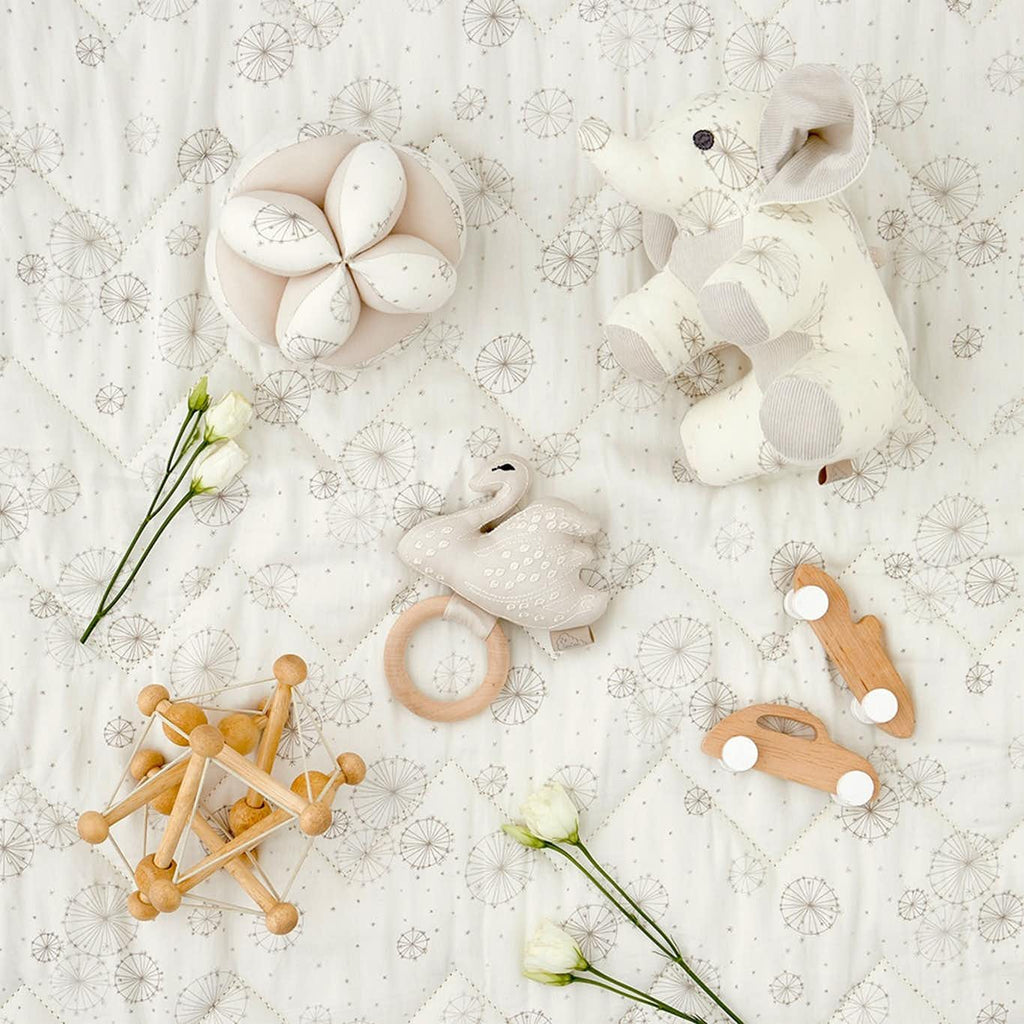 Palla montessoriana in cotone con stampe di piccoli fiori su fondo bianco con altri oggetti