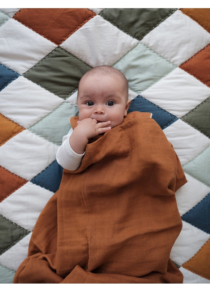 Neonato disteso sulla coperta a rombi colorati su sfondo bianco